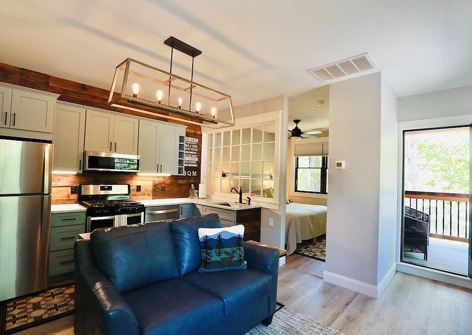 Full kitchen with table behind the couch, king bedroom and entry to the Screen Porch.
