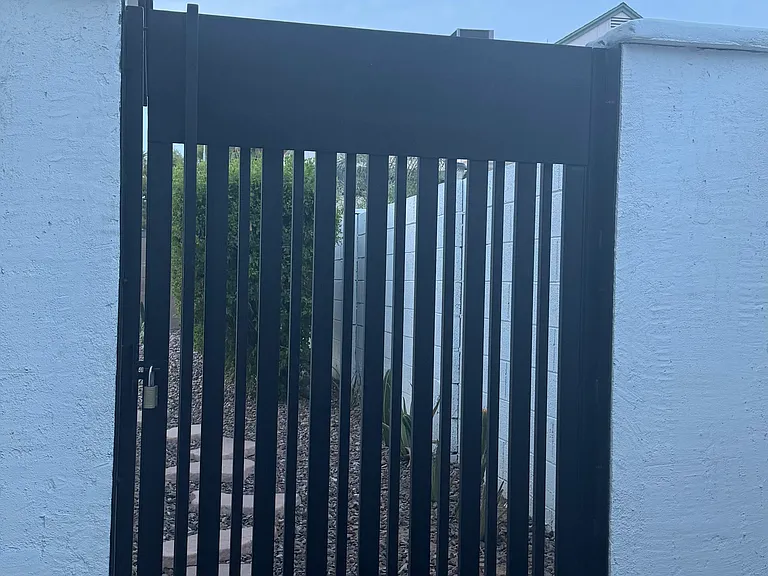 EXTERIOR. Sleek metal gate opening to the backyard.