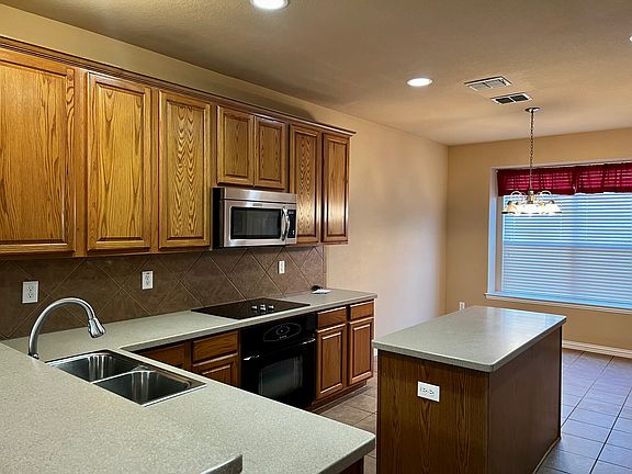 The kitchen includes stainless steel and black appliances, Korean countertops, and lots of storage space