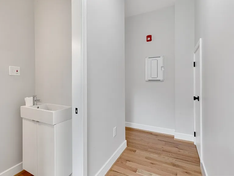 Looking back towards the front hall from the bottom of the stairs. The powder room with pocket-door is on the left and beyond that is the hallway back to the main common space. On the right is storage closet.