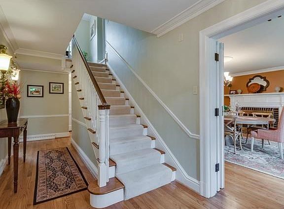 The entrance hall with traditional staircase, chair rail, crown molding and beautiful wood floor is perfect to greet guests