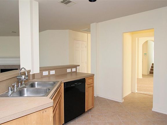 Kitchen has double stainless steel sinks, dishwasher, and breakfast bar that opens into the living a