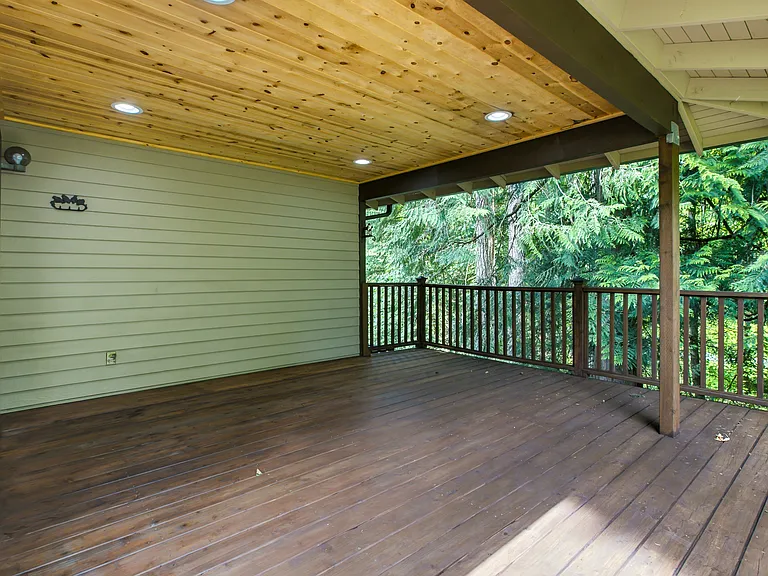 Very large covered deck looks over the treed yardspace.