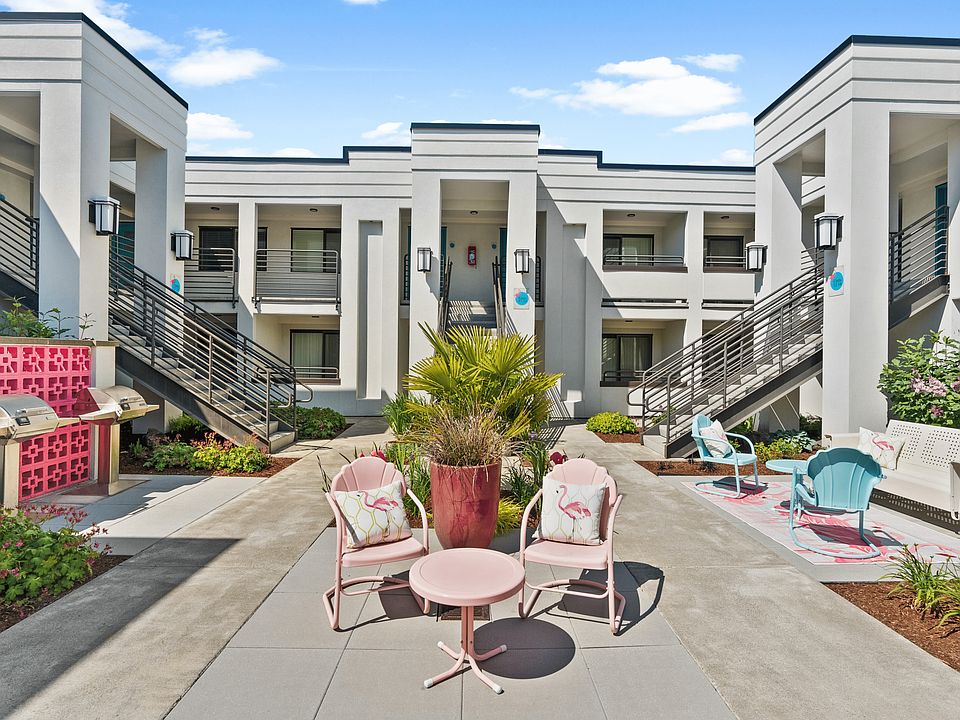 Elegant apartment courtyard with modern architecture, lush greenery, and charming outdoor seating, perfect for relaxation and social gatherings.
