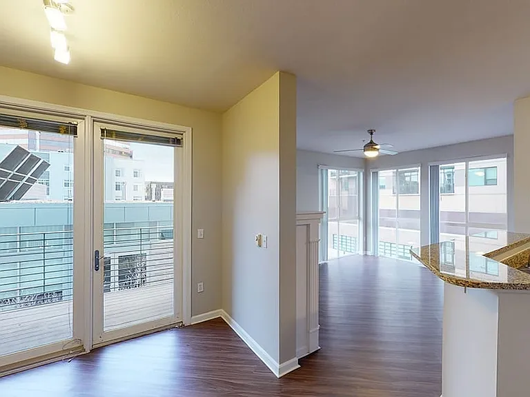 Apartment living room with wood-style flooring with balcony or patio in select homes.