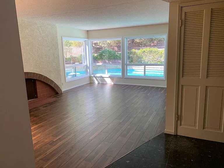View of pool and private hillside from living room. Tons of natural light enhance the large living space.