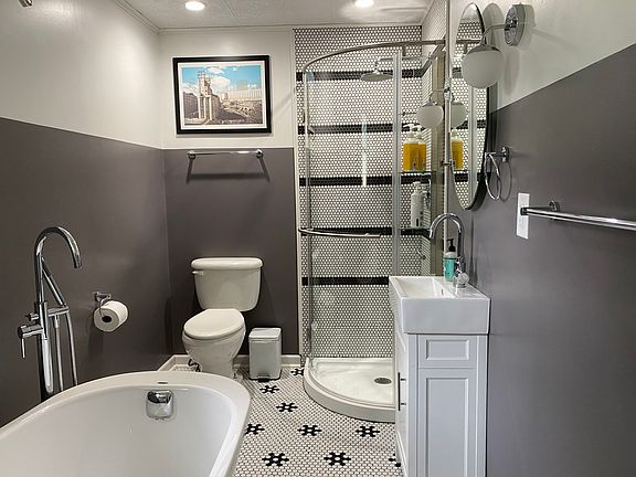 Main floor bathroom with custom tile work, a freestanding soaker tub, and a corner shower