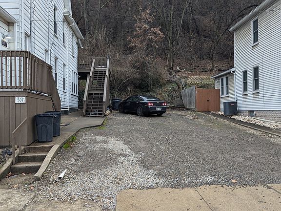 View of driveway and steps to back yard and deck