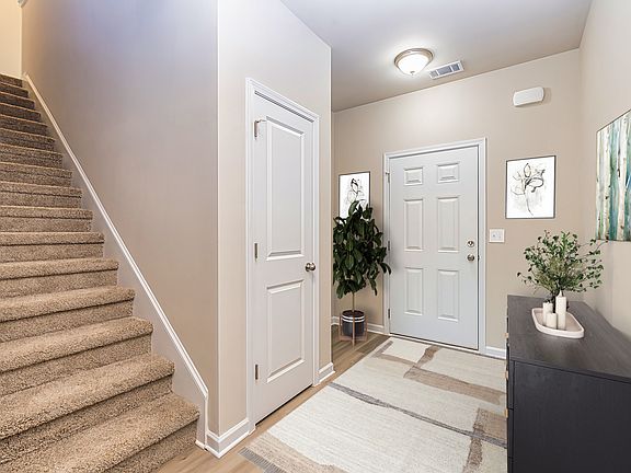 Foyer and Stairs: Inviting entryway, neutral tones, and convenient access to stairs and a coat closet.