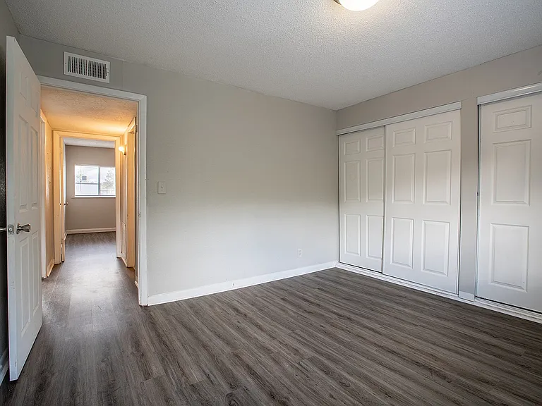 Bright, spacious bedroom with sleek wood flooring and ample closet space, offering a versatile canvas for personalized decor.