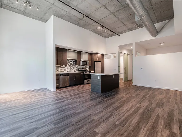Open living/work space with high ceilings and hardwood flooring in Live and Work apartment at 1400 FIG Apartments in Los Angeles, California.