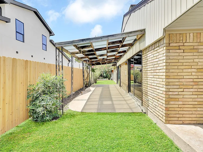 Grass on both sides of the patio and a small garden area at the back, plus a storage building.