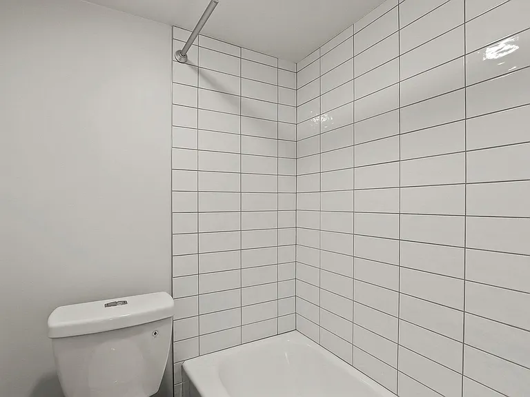 Modern bathroom with elegant white subway tiles and a pristine white bathtub, offering a clean and inviting atmosphere.