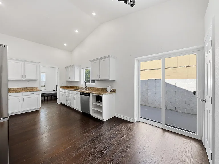 Spacious kitchen with ample white cabinetry, granite counters, and a dishwasher, plus sliding doors to a private patio.