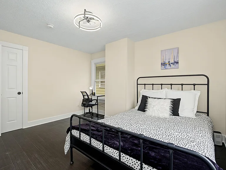 Furnished bedroom with a metal bed frame, dedicated desk nook, and double-door closet for convenient storage.