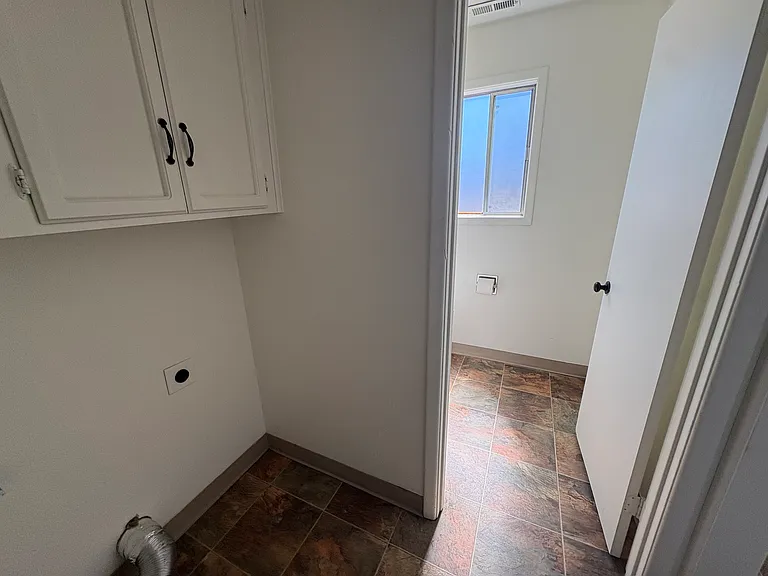 Utility room on main level, located at end of kitchen, doorway to half bath