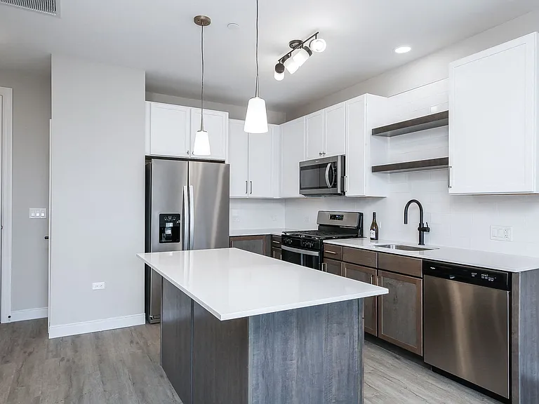 Kitchen with stainless steel whirlpool appliances, quartz countertops, floating shelves and two tone cabinets