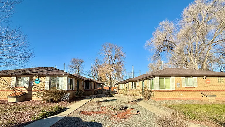 Charming brick duplexes with spacious front yards and clear blue sky in a tranquil neighborhood setting.