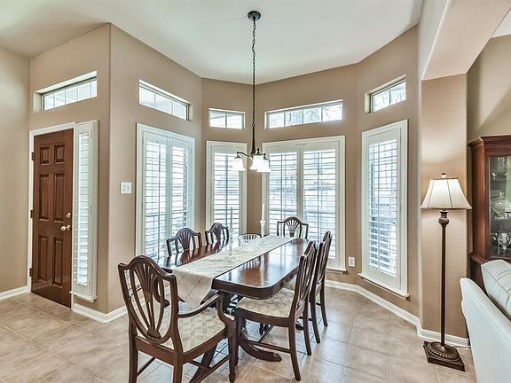 The dining room is located to the left of the entry way with tile floors and bay windows with plantation shutters.