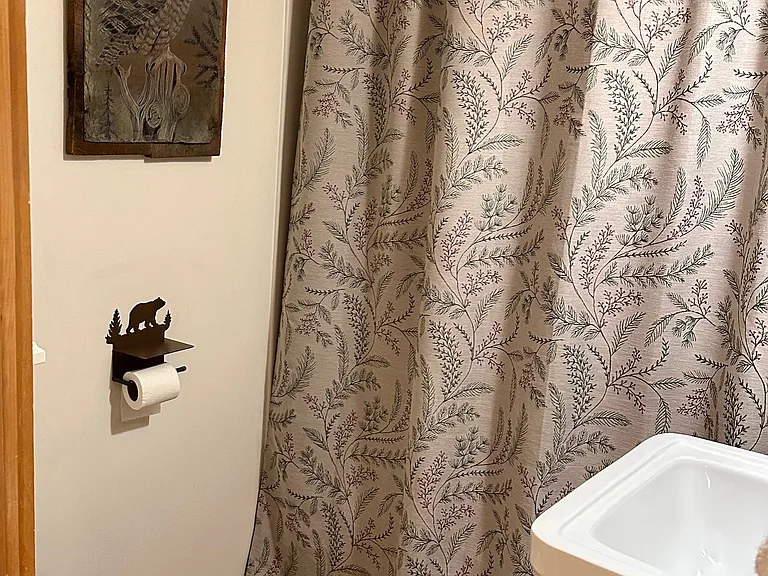 Full Bathroom with tub shower, sink, and toilet. Slate etching of an owl and Black Forest Decor toilet paper holder with bear motif.