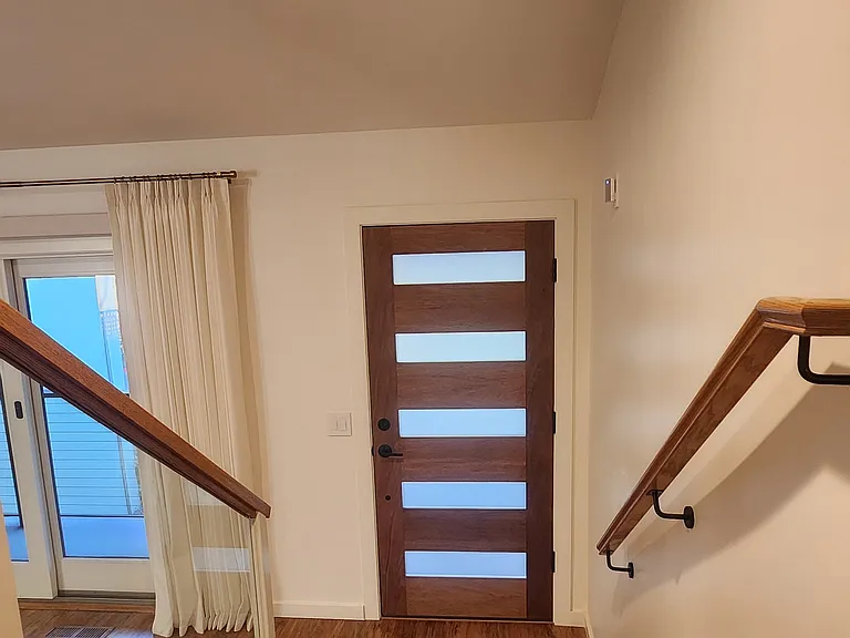 Front door view from upstairs split-level. Solid mahogany door. Tempered, laminated glass, modern railing