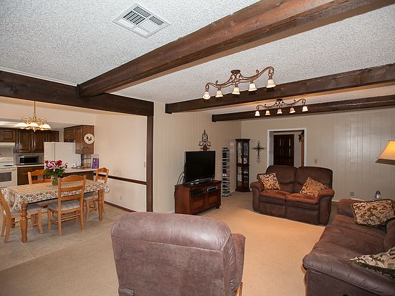 Beamed ceiling in living room open to dining and kitchen