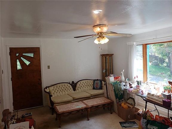 Large living room with ceiling fan, picture window and deco fireplace.  All carpeting needs replaced
