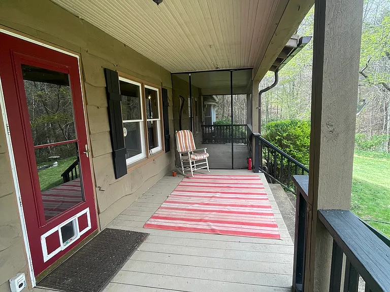 Front porch off the living room overlooks a sloped meadow down to the river
