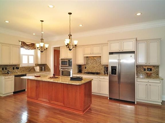 Cook's kitchen with island, stainless steel appliances, pendant lights