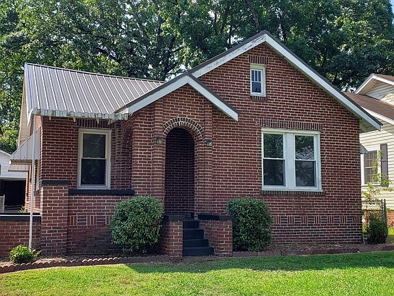 Brick home with metal roof and new vinyl windows. Covered front porch. 2 car garage.