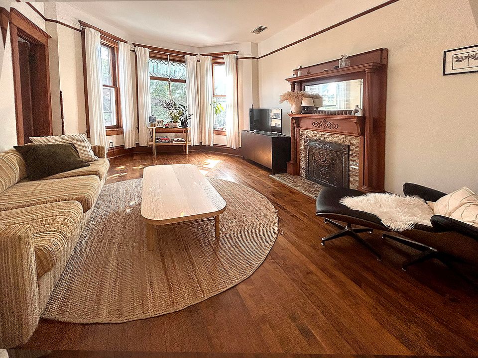 Living room has bay window with leaded glass, decorative mantle and high ceilings