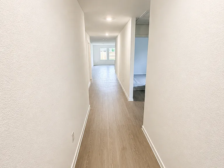 Elegant extended hallway with modern finishes, recessed lighting, and durable wood-look flooring that creates a bright and spacious atmosphere.