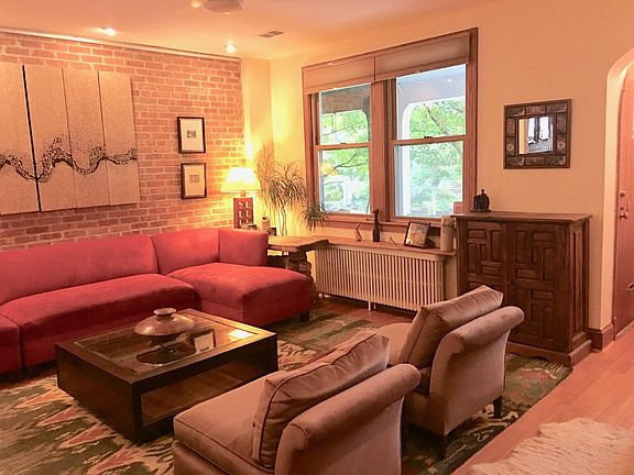 Large open living room, with coat closet, ceiling fan, exposed brick accent wall