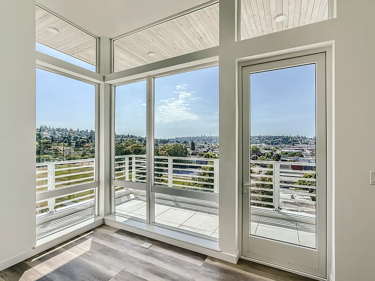 Enjoy the natural light and city views from this spacious living room at Anker Ballard, featuring large windows and an open layout.