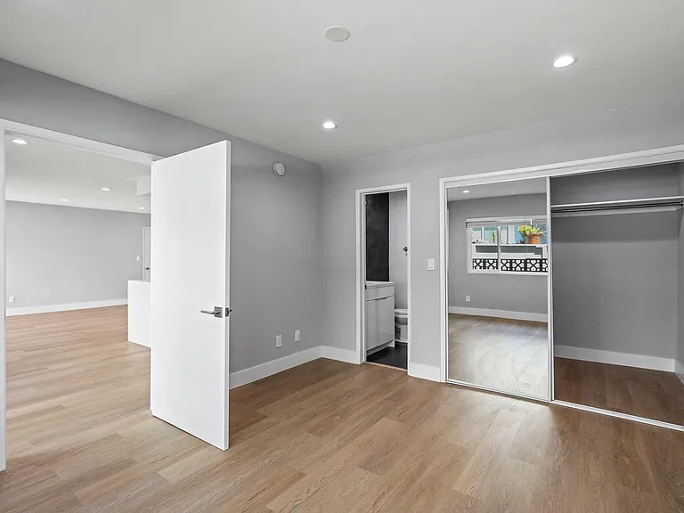 Bedroom with Mirrored Closet, Recessed Lighting, Vinyl Flooring, and Bathroom