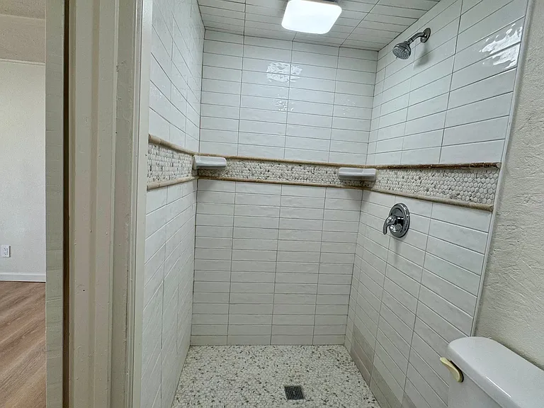 Open walk-in shower with custom tile and new shower faucet.