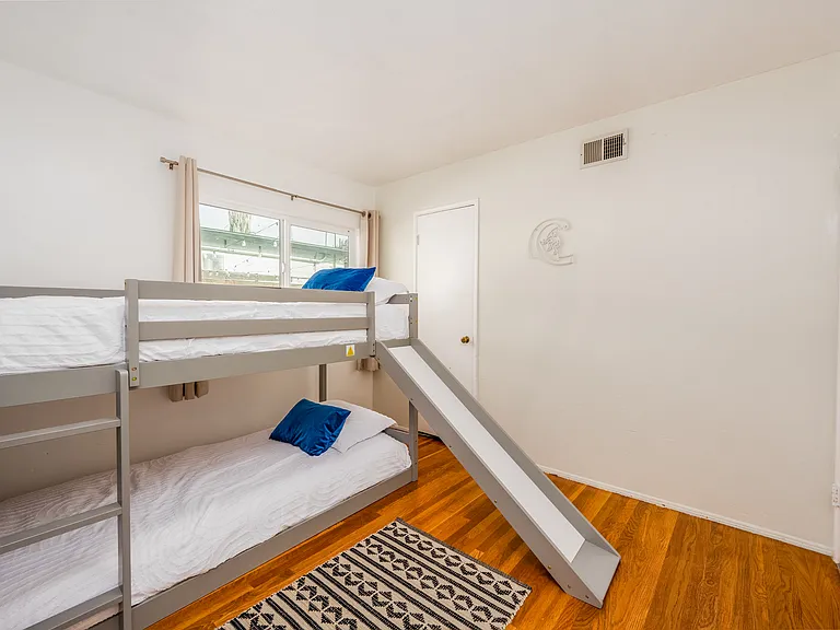 Hardwood floors, a cozy rug, and natural greenery create a warm, inviting atmosphere. Wake up to sunlight streaming through the windows, and enjoy a space that feels like a getaway within your getaway. Perfect for creating unforgettable memories!