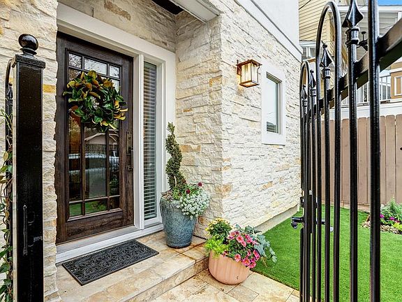 Front yard is enclosed with a wrought-iron fence & gate and was recently landscaped with artificial turf.