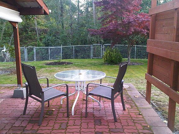 Across the back patio to the creek, with pasture beyond the trees.