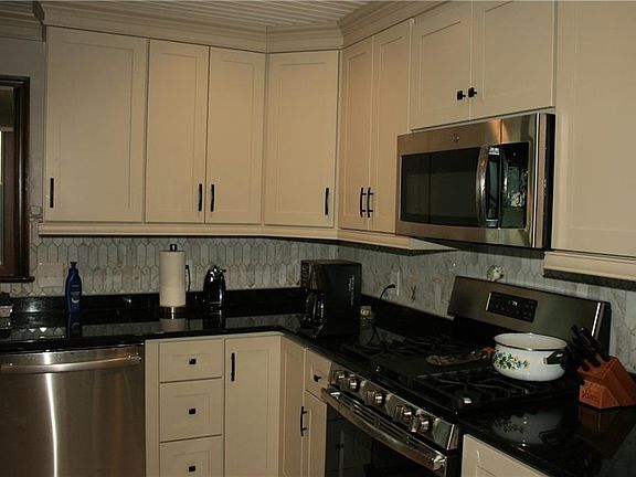 Beautifull remodeled kitchen has loads of cabinets, granite countertops, stainless appliances, stainless farm sink, marble tile backsplash and custom tile floors.