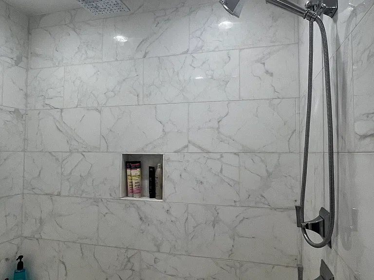 Master shower with two shower heads, and full-length bench, and two niches for products.