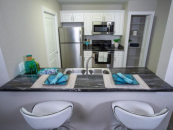 Your newly renovated kitchen features black-fusion countertops, wood-style flooring, and stainless steel appliances.