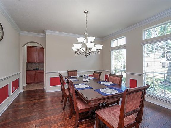 Large formal dining room featuring custom molding, wood floors, and elegant lighting feature.