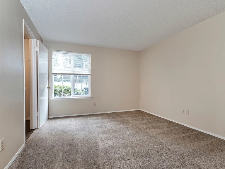 Spacious, unfurnished bedroom with neutral tones, plush carpeting, and a bright window. Spacious, unfurnished bedroom with neutral tones, plush carpeting, and a bright window.