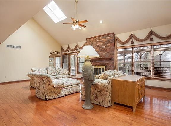 The great room has vaulted ceilings, skylights, wood floors and a fireplace.