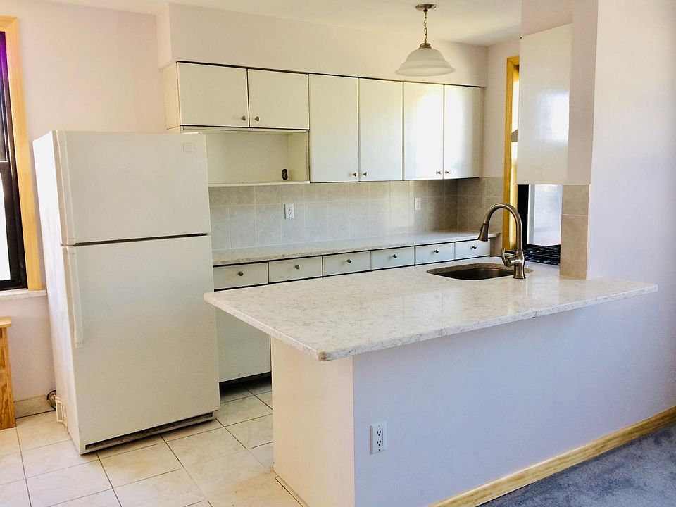 Brightly-lit kitchen with new quartz countertops, sink, dishwasher, oven and stove