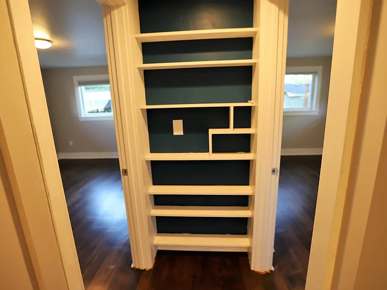Bookshelf at end of hallway. Bed 1 to the left, Bed 2 to the right.