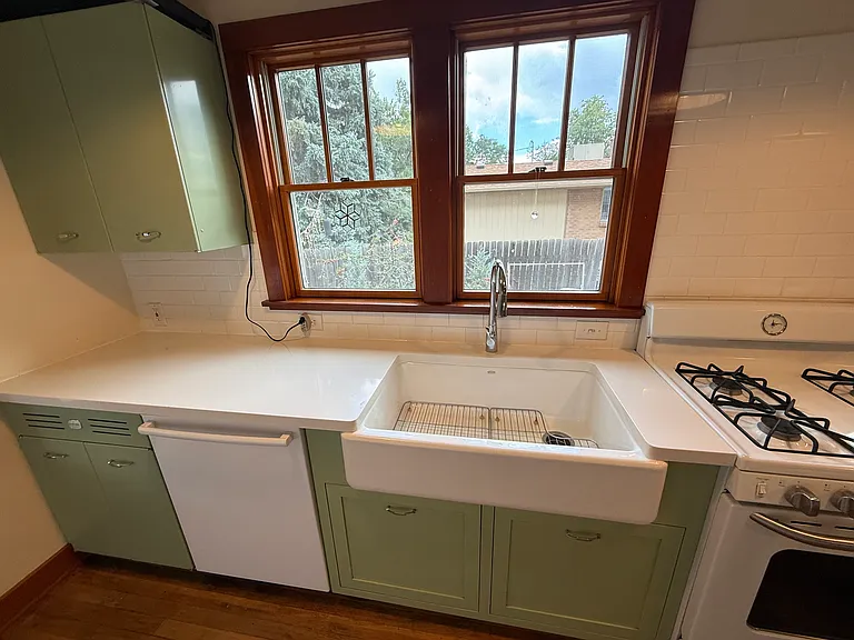 Renovated kitchen with apron-front farmhouse sink and wood-trimmed windows
