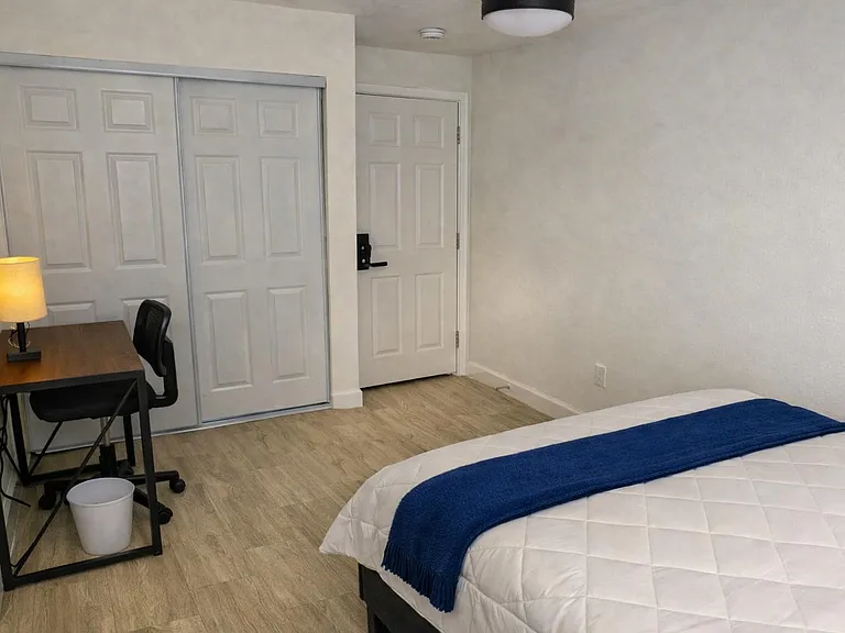 Private bedroom with a comfortable bed, dedicated desk workspace, and a sliding-door closet for convenient storage.