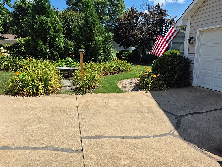 Cobblestone walk to exterior trash can enclosure.